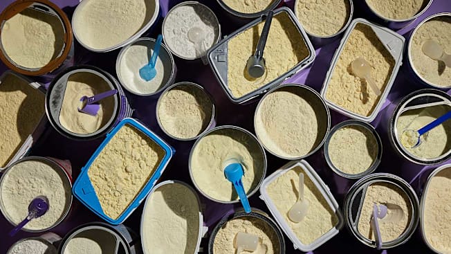 Open containers of baby formula with scoops representing prep choices